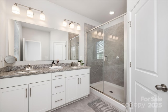 bathroom featuring tile patterned floors, a shower with shower door, and vanity