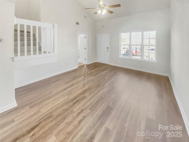 empty room with ceiling fan, high vaulted ceiling, and light wood-type flooring