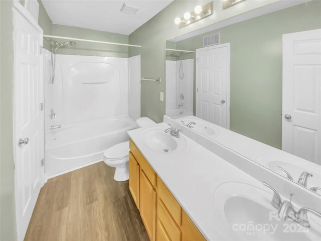 full bathroom featuring wood-type flooring, vanity, washtub / shower combination, and toilet