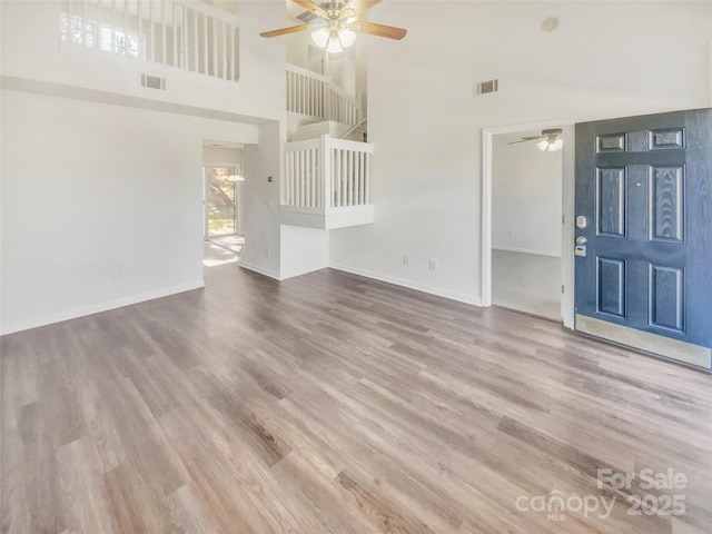 unfurnished living room featuring a towering ceiling, ceiling fan, and hardwood / wood-style flooring