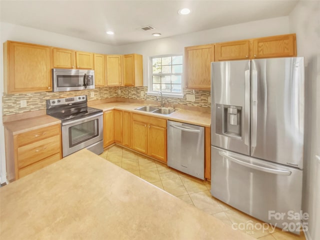 kitchen featuring tasteful backsplash, appliances with stainless steel finishes, sink, and light tile patterned floors