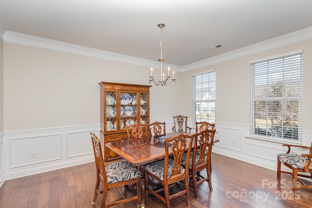 dining space featuring an inviting chandelier, ornamental molding, and hardwood / wood-style flooring