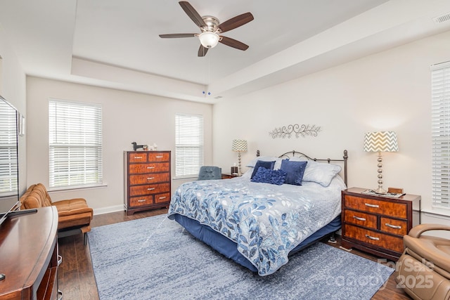 bedroom featuring ceiling fan, dark hardwood / wood-style floors, and a raised ceiling