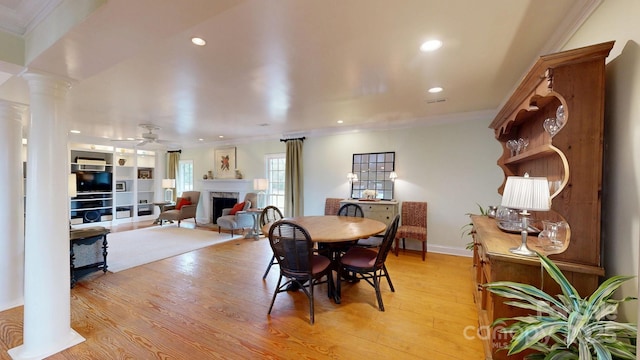 dining area featuring decorative columns, crown molding, ceiling fan, and light hardwood / wood-style flooring