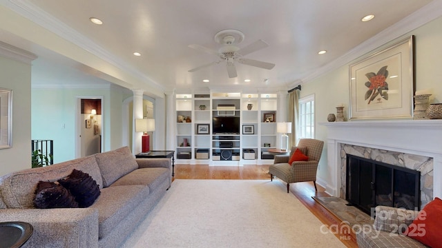 living room with hardwood / wood-style floors, crown molding, a fireplace, and ceiling fan