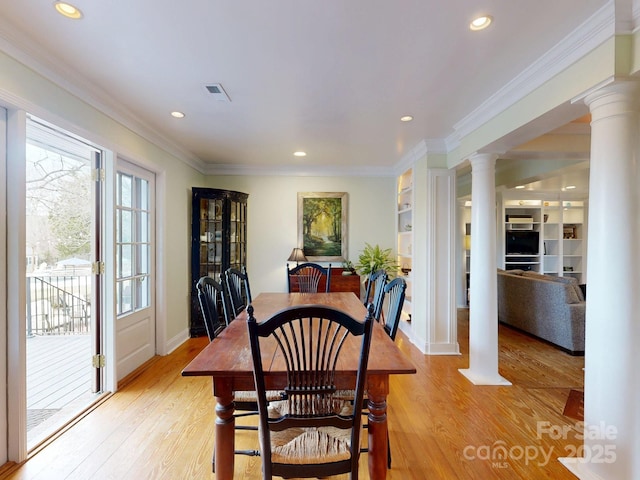 dining room featuring crown molding, built in features, decorative columns, and light hardwood / wood-style flooring