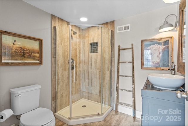 bathroom featuring hardwood / wood-style flooring, vanity, toilet, and an enclosed shower