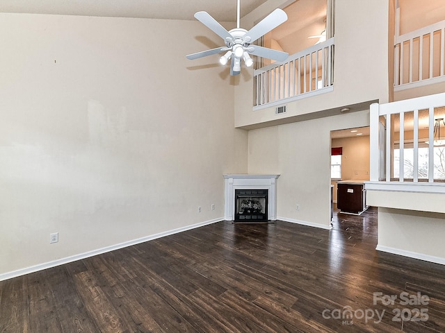 unfurnished living room featuring dark hardwood / wood-style flooring, ceiling fan, and high vaulted ceiling