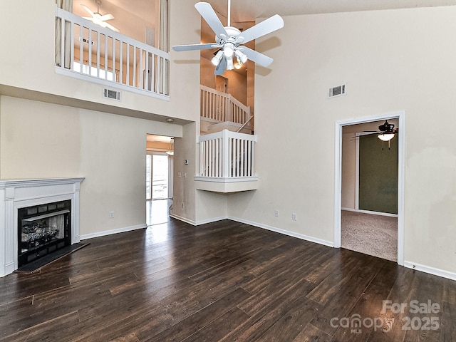 unfurnished living room with ceiling fan, dark wood-type flooring, and high vaulted ceiling