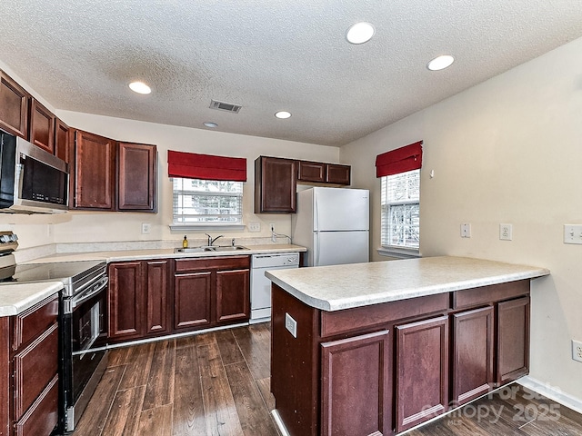 kitchen featuring appliances with stainless steel finishes, sink, kitchen peninsula, dark wood-type flooring, and a textured ceiling