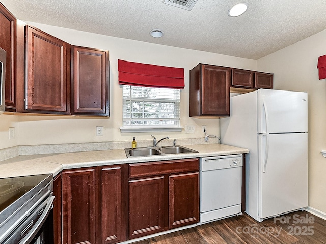 kitchen featuring dark wood-type flooring, white appliances, sink, and a textured ceiling