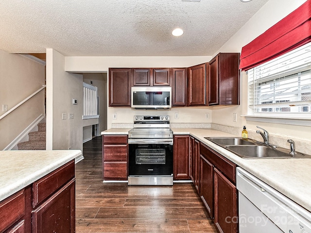 kitchen featuring appliances with stainless steel finishes, dark hardwood / wood-style flooring, sink, and a textured ceiling