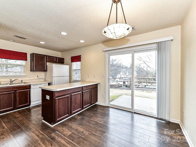 kitchen with sink, hanging light fixtures, dark hardwood / wood-style floors, kitchen peninsula, and white appliances