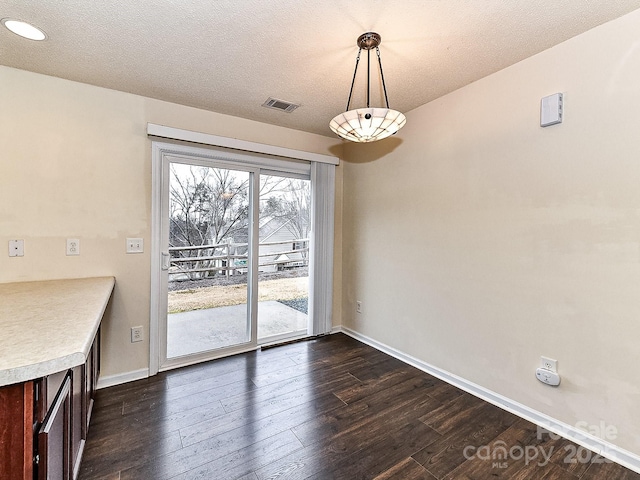 unfurnished dining area with dark hardwood / wood-style floors and a textured ceiling