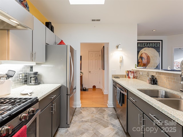 kitchen featuring stainless steel appliances, gray cabinets, exhaust hood, and light stone counters