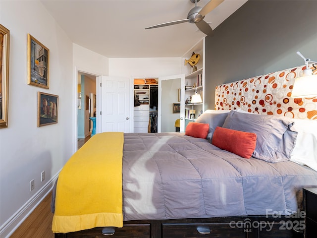 bedroom with hardwood / wood-style flooring, a walk in closet, ceiling fan, and a closet