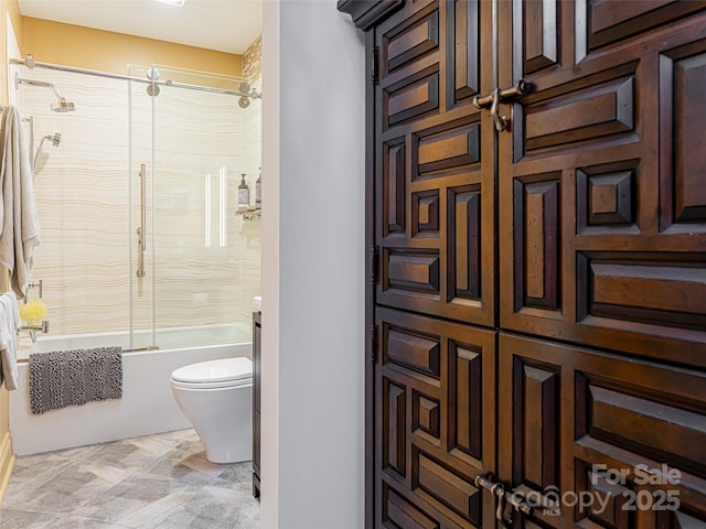 bathroom featuring combined bath / shower with glass door and toilet