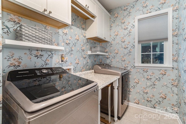 laundry area featuring cabinets, washer and dryer, and light tile patterned floors