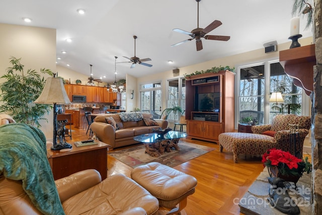 living room featuring light hardwood / wood-style flooring, ceiling fan, and vaulted ceiling