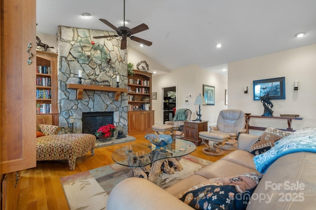 living room with vaulted ceiling, ceiling fan, a fireplace, and light hardwood / wood-style flooring