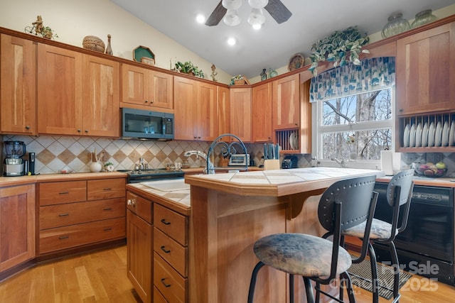 kitchen featuring lofted ceiling, a breakfast bar area, tile counters, a kitchen island, and decorative backsplash