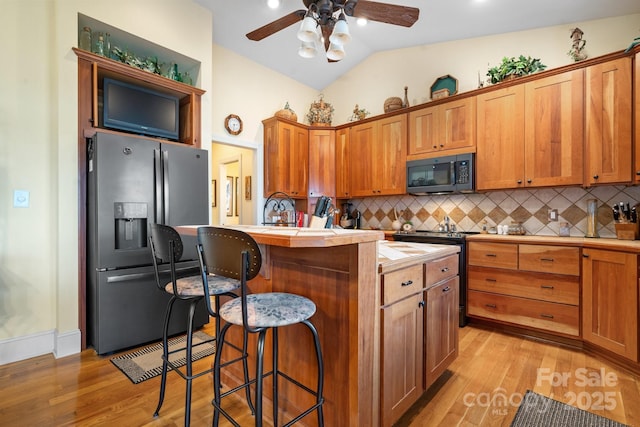 kitchen featuring stainless steel fridge, backsplash, a center island, a kitchen bar, and vaulted ceiling