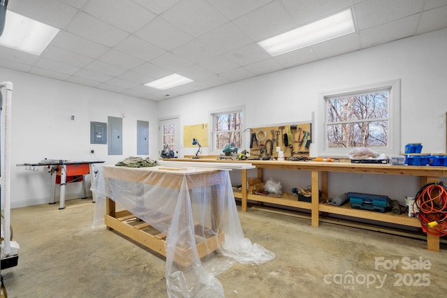 miscellaneous room featuring a paneled ceiling, electric panel, and a workshop area