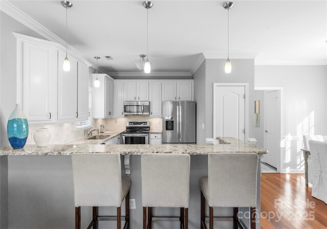 kitchen featuring appliances with stainless steel finishes, white cabinetry, and decorative light fixtures