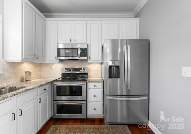 kitchen with stainless steel appliances, white cabinetry, decorative backsplash, and light stone countertops