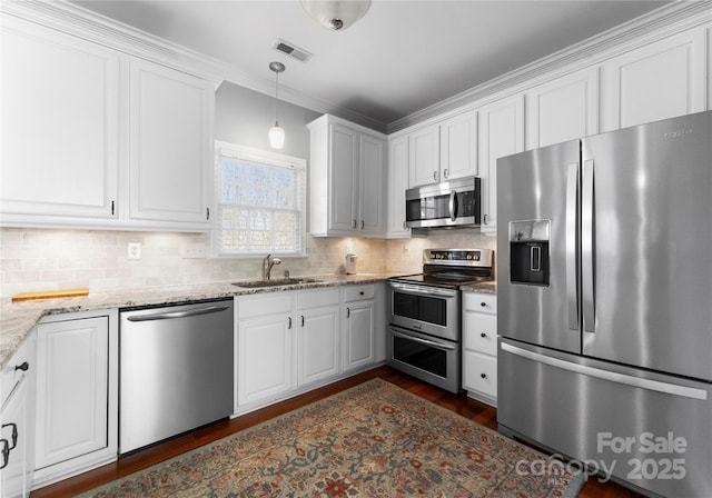 kitchen featuring visible vents, hanging light fixtures, appliances with stainless steel finishes, white cabinetry, and a sink