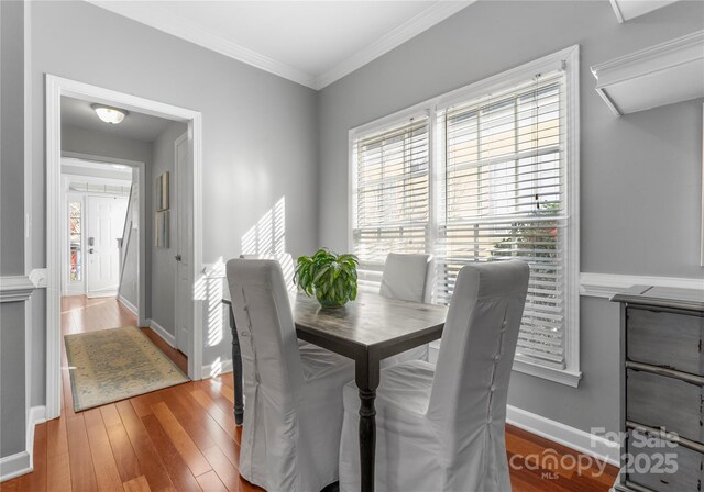 dining room with crown molding, baseboards, and wood finished floors