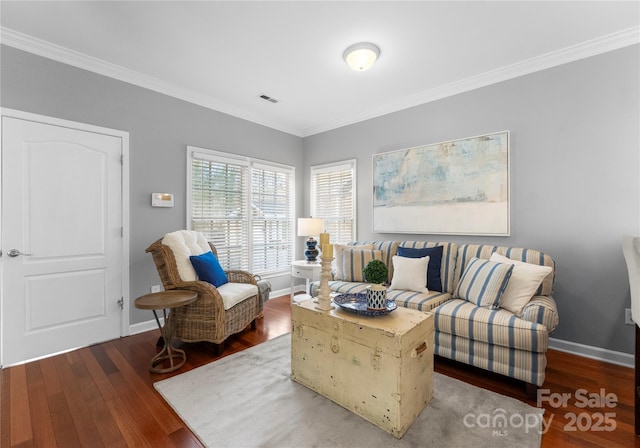 living area with ornamental molding, wood finished floors, visible vents, and baseboards