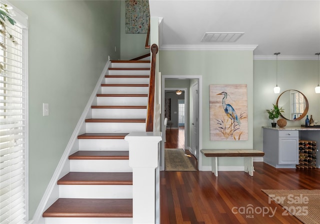 stairs with ornamental molding, visible vents, baseboards, and wood finished floors