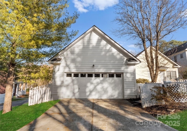 view of side of home with a garage, an outbuilding, and fence