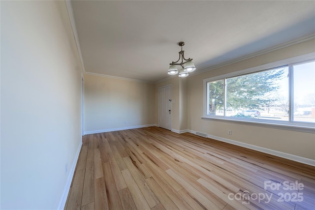 spare room with ornamental molding, a notable chandelier, and light hardwood / wood-style flooring