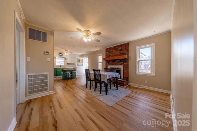 dining area with plenty of natural light, a fireplace, and light hardwood / wood-style floors