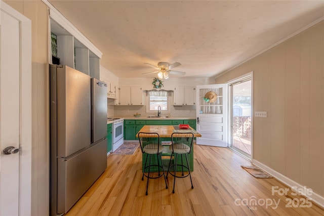 kitchen with a kitchen island, white range with electric stovetop, stainless steel refrigerator, sink, and white cabinets