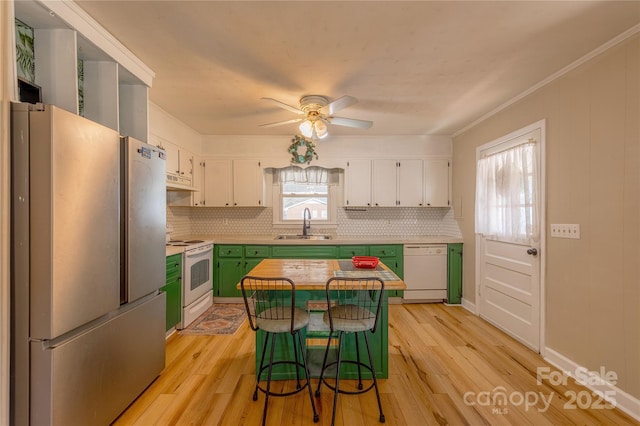 kitchen with white appliances, a breakfast bar, a center island, green cabinetry, and white cabinets