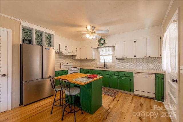 kitchen featuring sink, white appliances, a kitchen bar, green cabinetry, and white cabinets