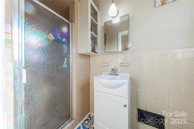 bathroom with tile walls, an enclosed shower, and vanity