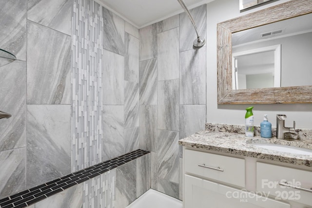 bathroom featuring a tile shower and vanity