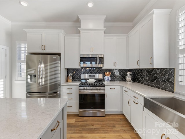 kitchen featuring white cabinetry, appliances with stainless steel finishes, light hardwood / wood-style floors, and light stone counters