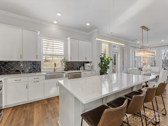 kitchen featuring hanging light fixtures, sink, a center island, and white cabinets