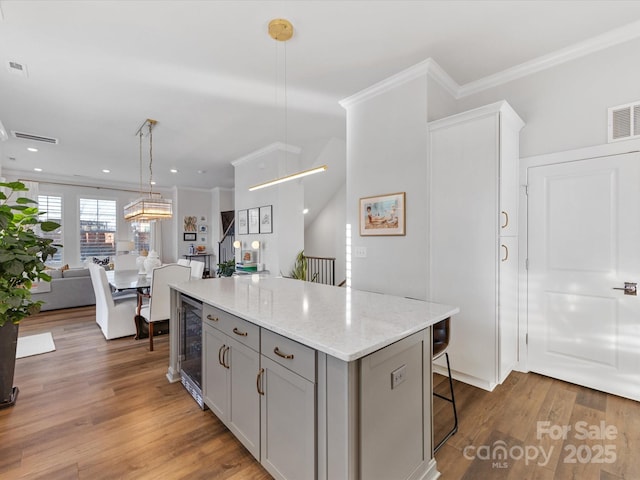 kitchen featuring gray cabinets, hardwood / wood-style floors, wine cooler, a kitchen island, and decorative light fixtures