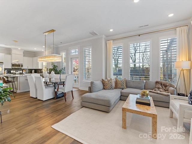 living room with crown molding and light wood-type flooring