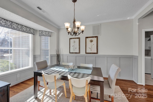 dining room featuring crown molding, a textured ceiling, and light hardwood / wood-style flooring