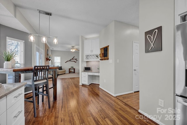 dining area featuring ceiling fan, dark hardwood / wood-style flooring, and built in desk