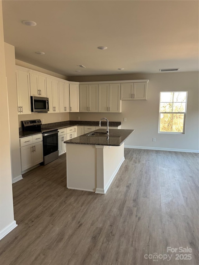 kitchen with sink, stainless steel appliances, dark stone counters, and white cabinets