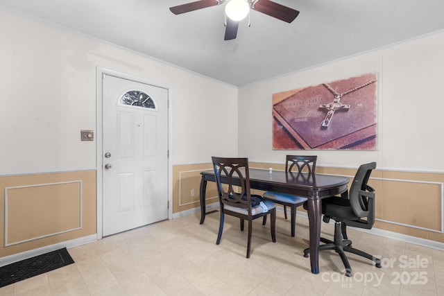 dining area with a decorative wall and ceiling fan