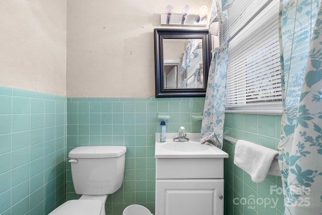 bathroom with tile walls, a wainscoted wall, toilet, and vanity